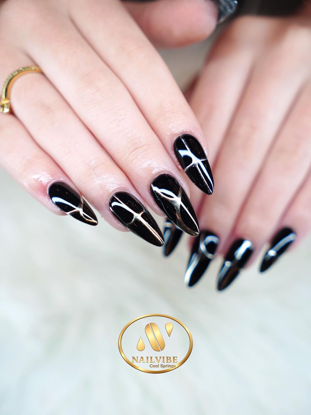 Glossy black stiletto nails with white art